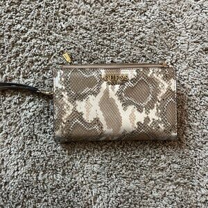 A Guess wallet that has a snake like pattern and is silver and mixes of browns.